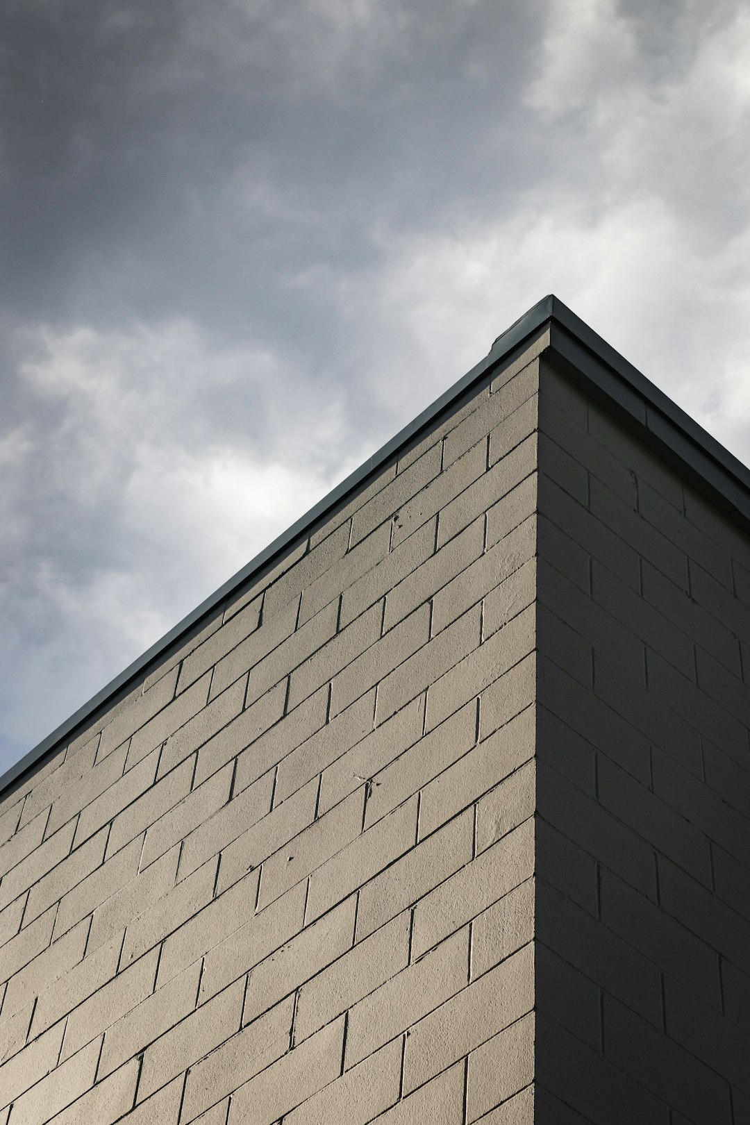 corner of brick wall with clouds behind